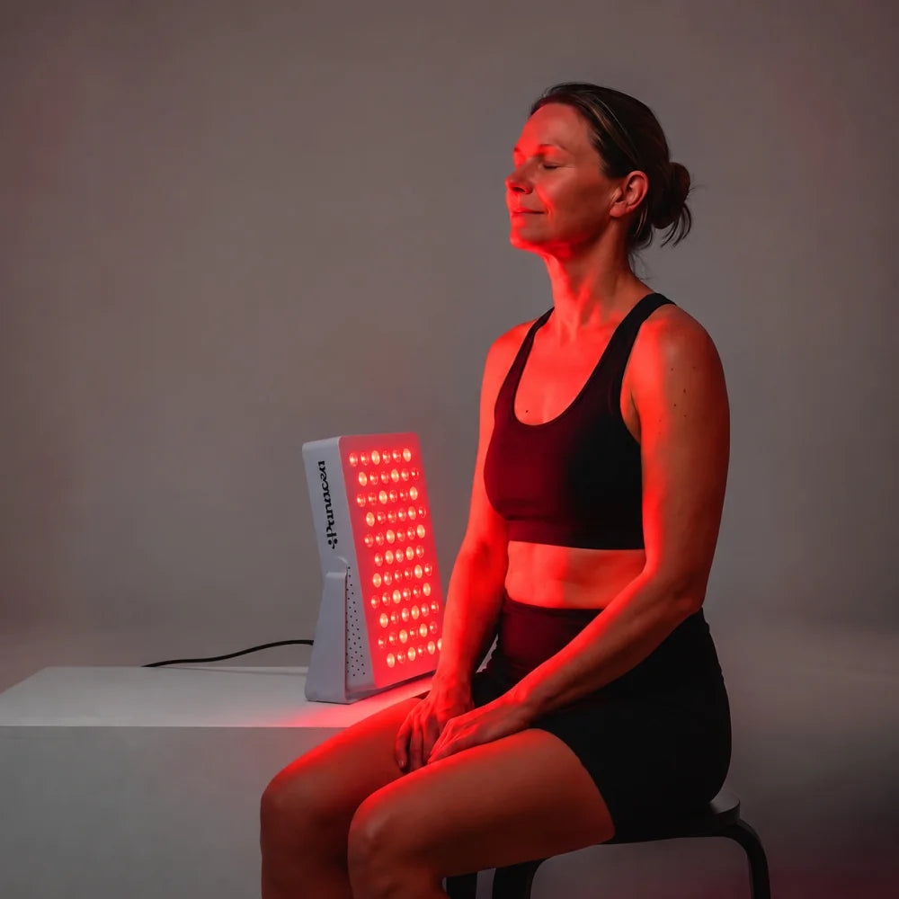Vrouw zit op een kruk naast de ATP Pure 300 op een tafel, rood licht op haar gezicht en bovenlichaam