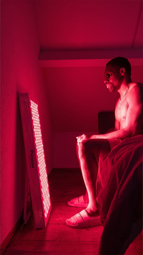 Man staat in het rode licht van een Panacea paneel in de slaapkamer